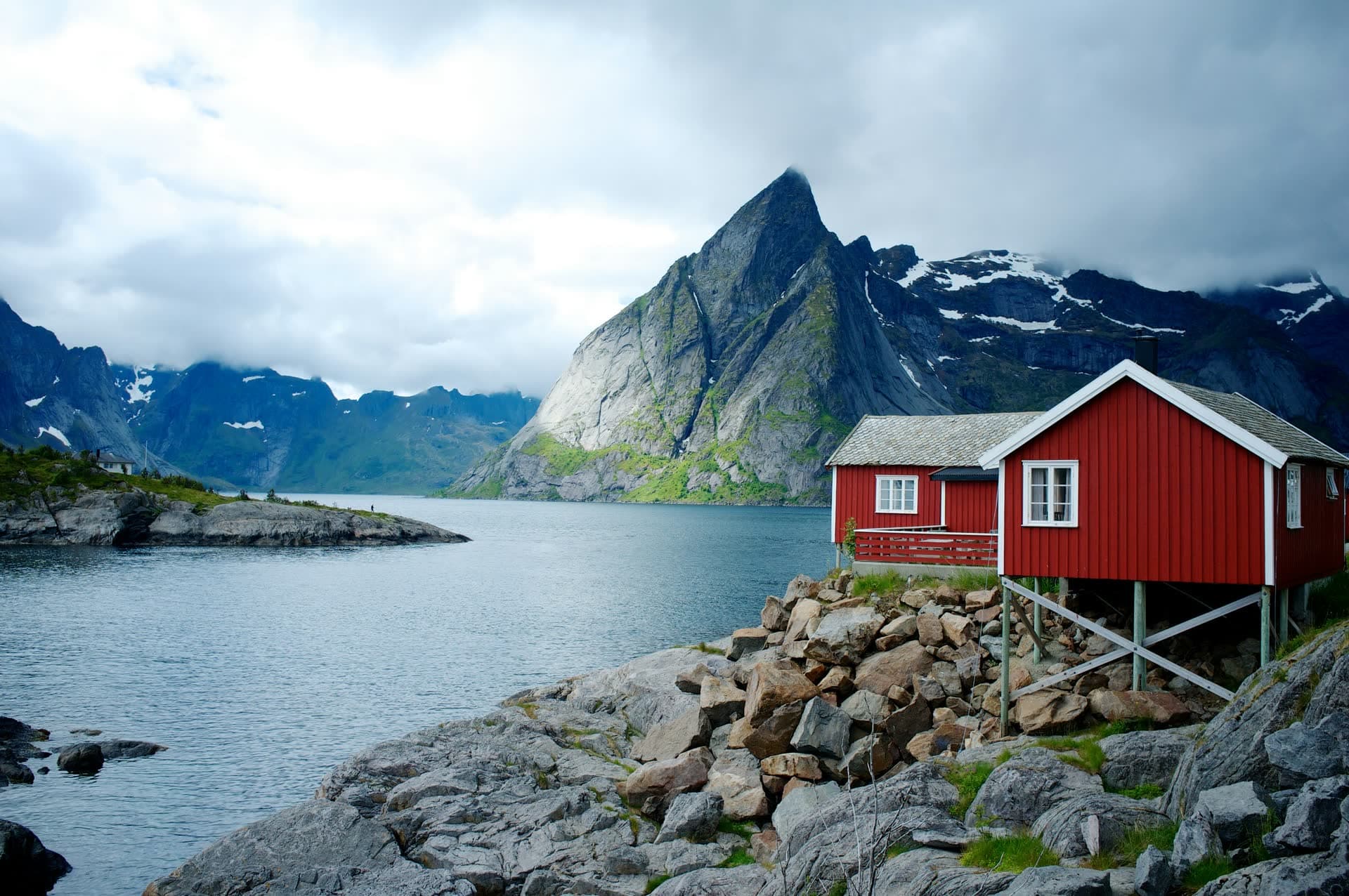 Cabane de pêcheur rouge devant les montagnes des Lofoten, en Norvège. Vivre en Norvège : notre fiche expatriation.