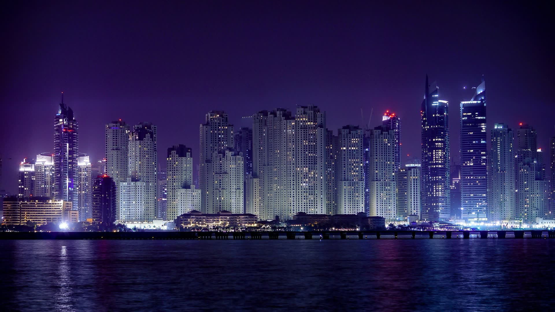 La skyline de Doha illuminée la nuit, au Qatar. Vivre au Qatar : notre fiche expatriation.