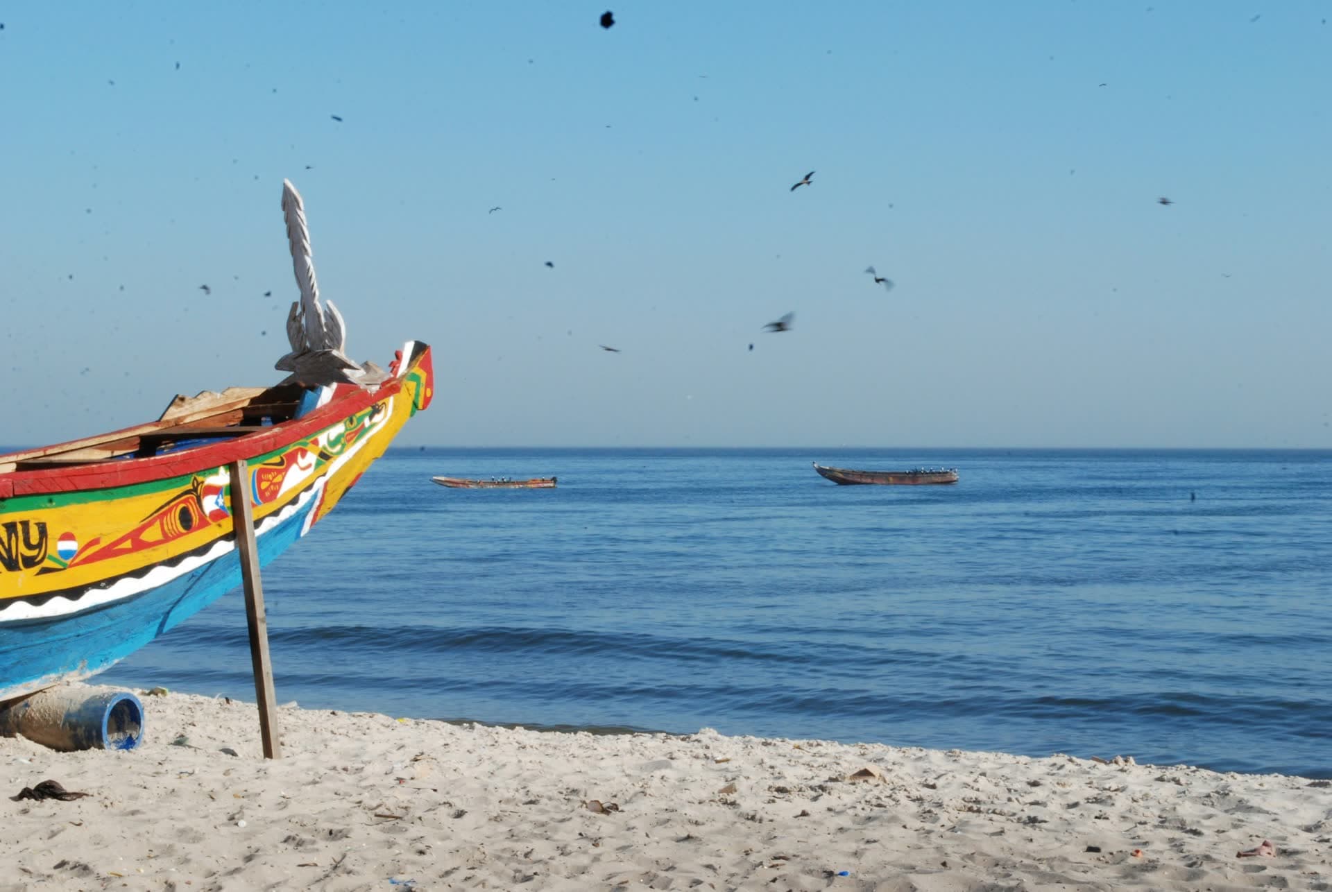 Pirogue colorée échouée sur une plage sénégalaise. Vivre au Sénégal : notre fiche expatriation.